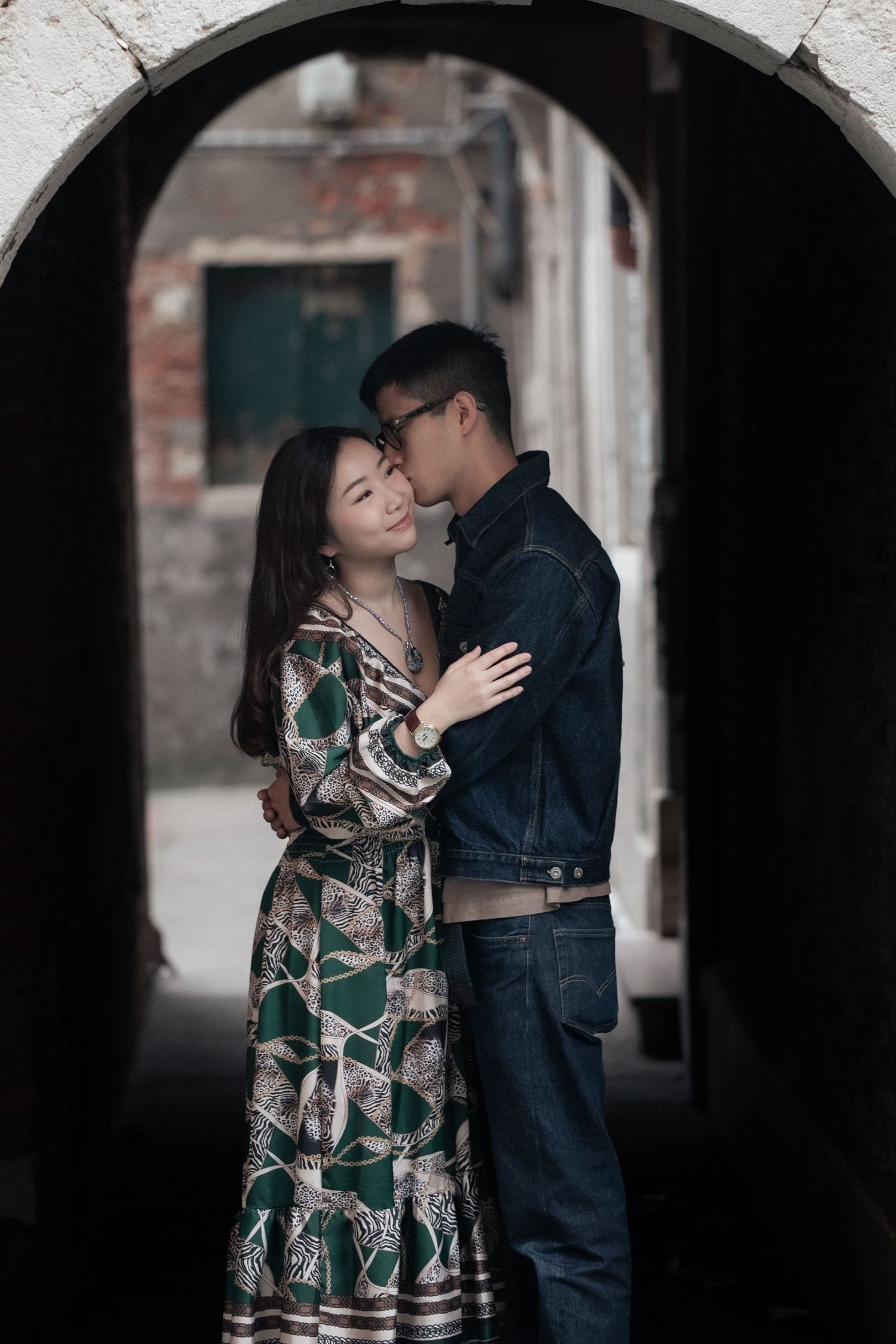 Couple embracing under a quiet stone arch during an intimate photo session in Venice.