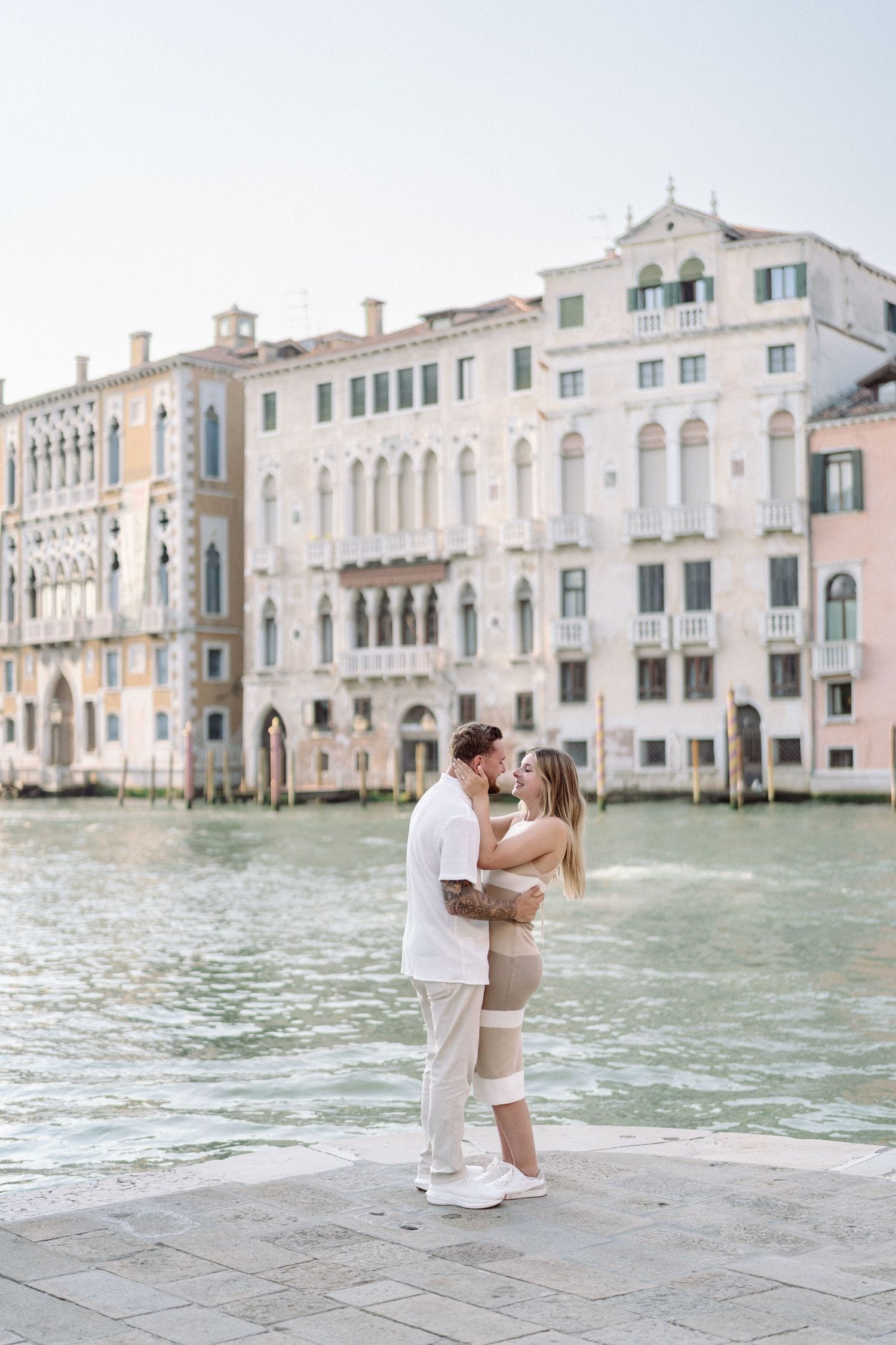 Newly engaged couple embracing by the Grand Canal after a Venice proposal