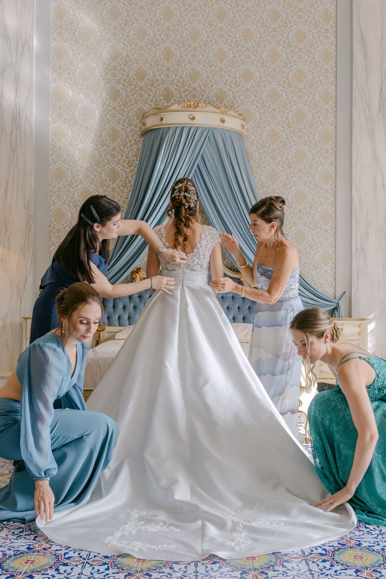Le damigelle aiutano la sposa a sistemare l’abito bianco prima del matrimonio.