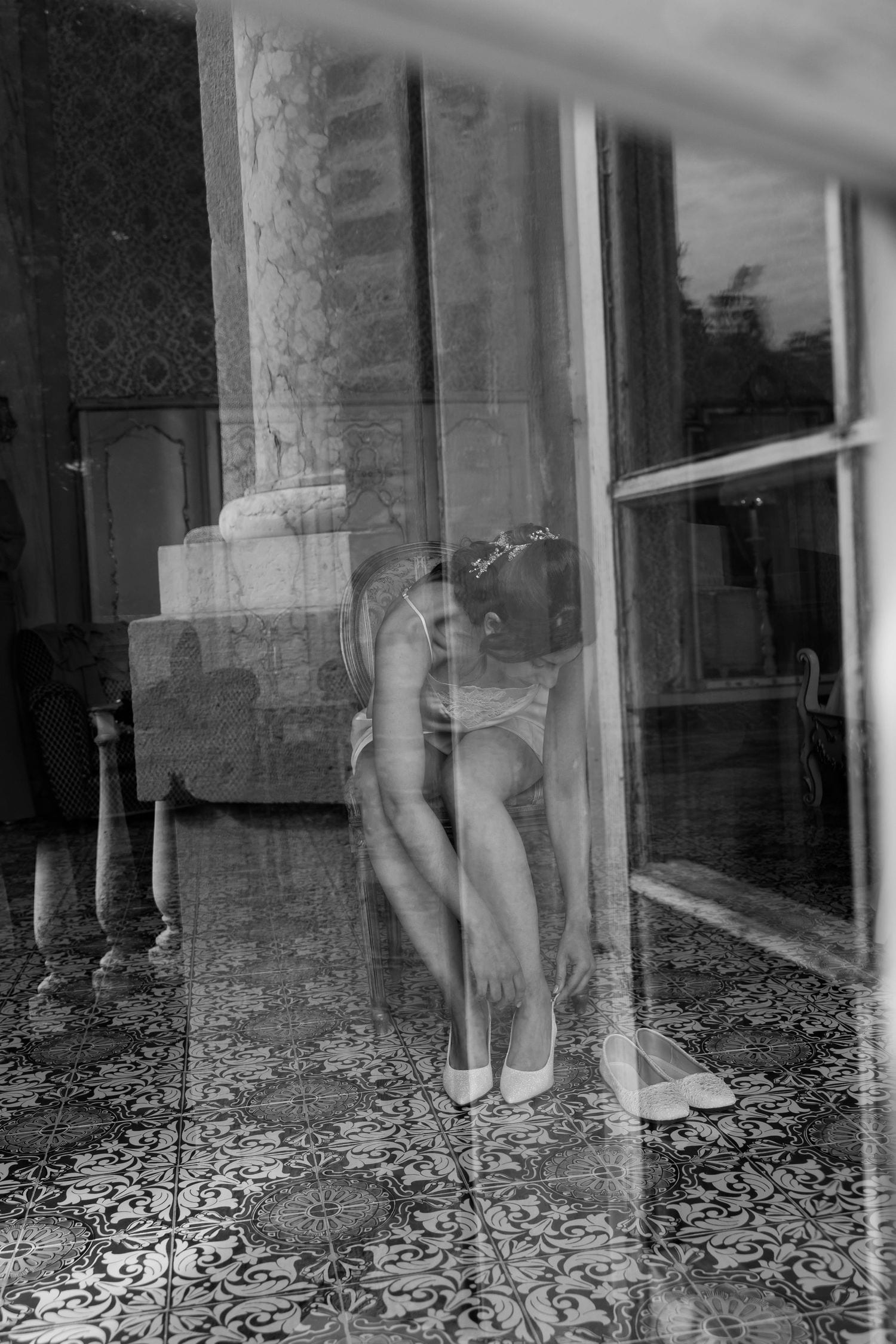 Scena artistica in bianco e nero attraverso una finestra con dettagli architettonici classici.