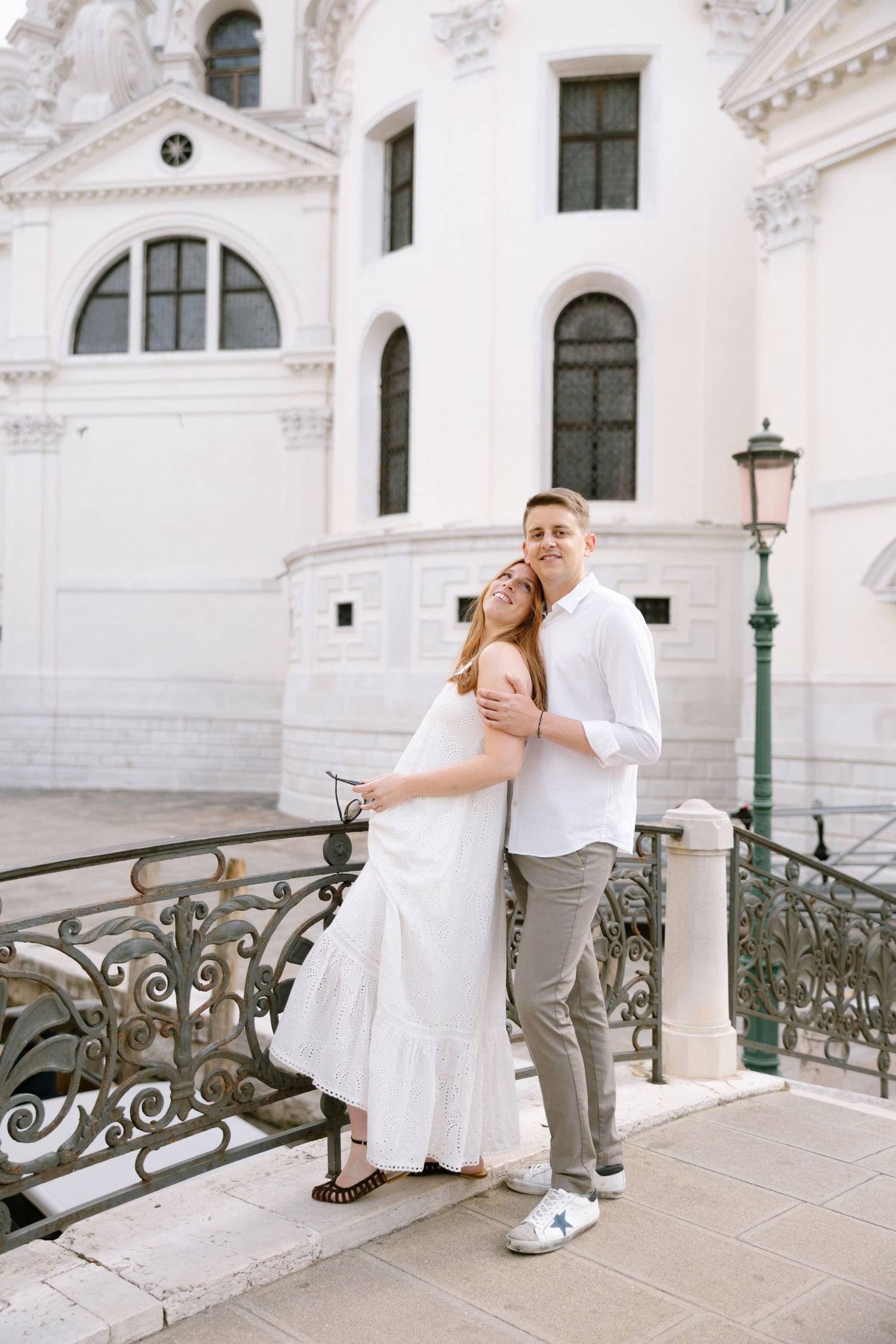 Playful dance moves captured against elegant white Venetian architecture and iron railings.