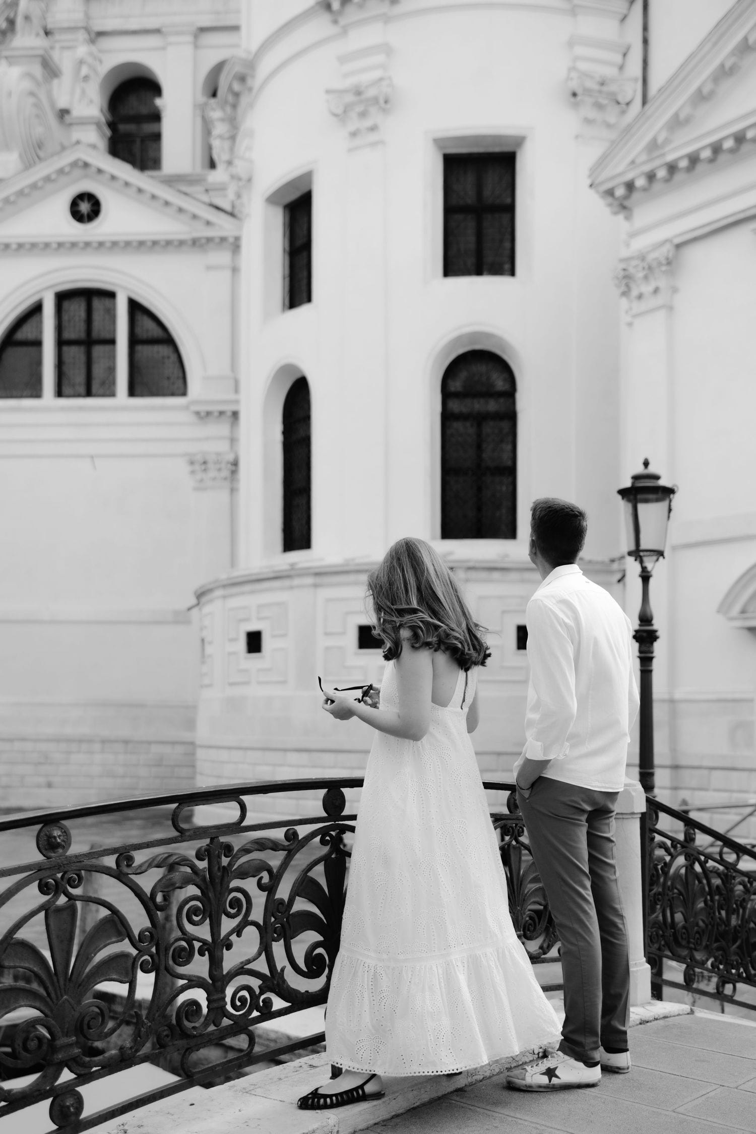 Romantic dance sequence on an ornate balcony against white architectural backdrop in Venice.