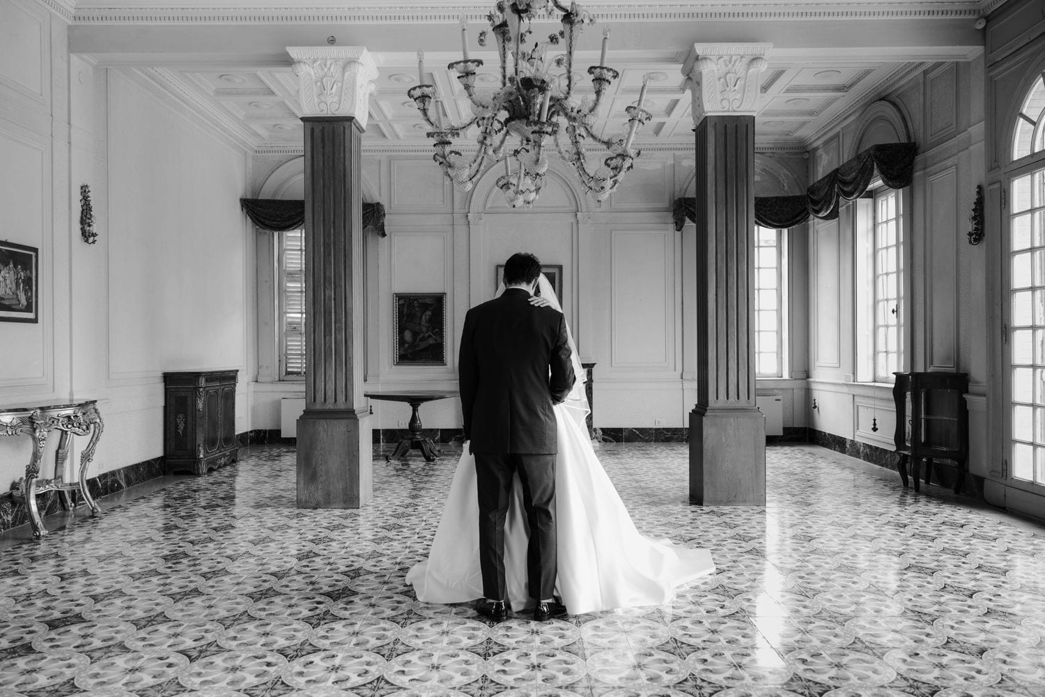 Momento intimo degli sposi in una sala elegante con lampadario.