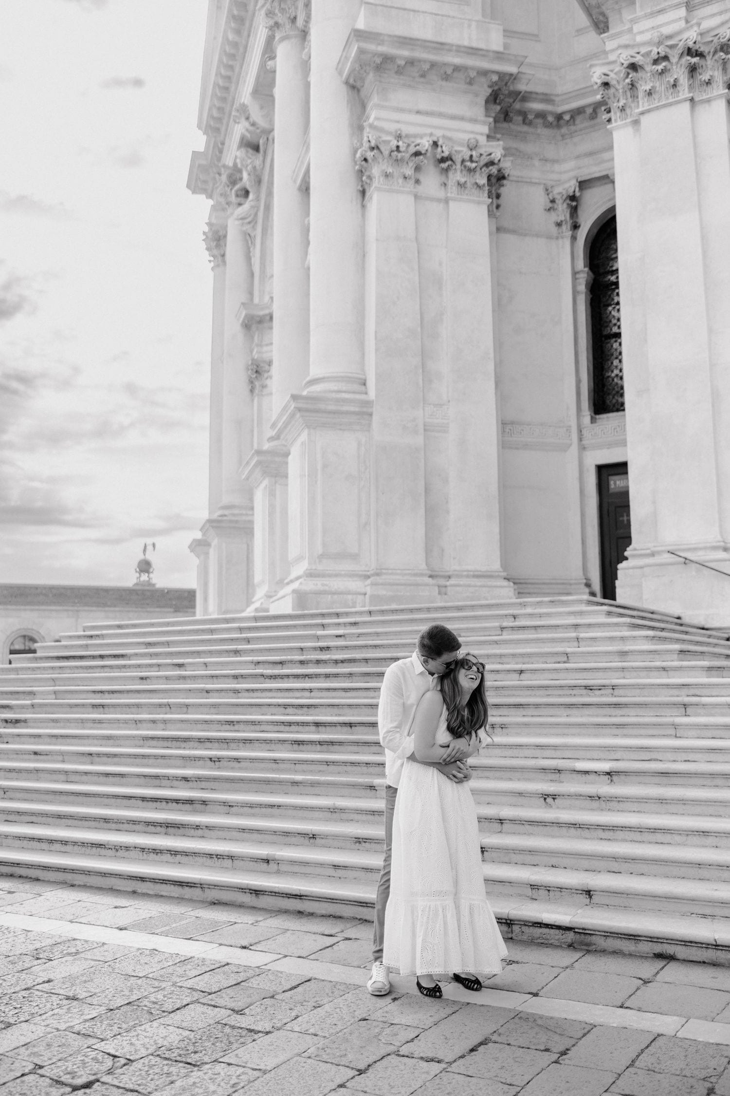 Black and white photo of graceful white dress movement along the steps of a grand Venetian cathedral.
