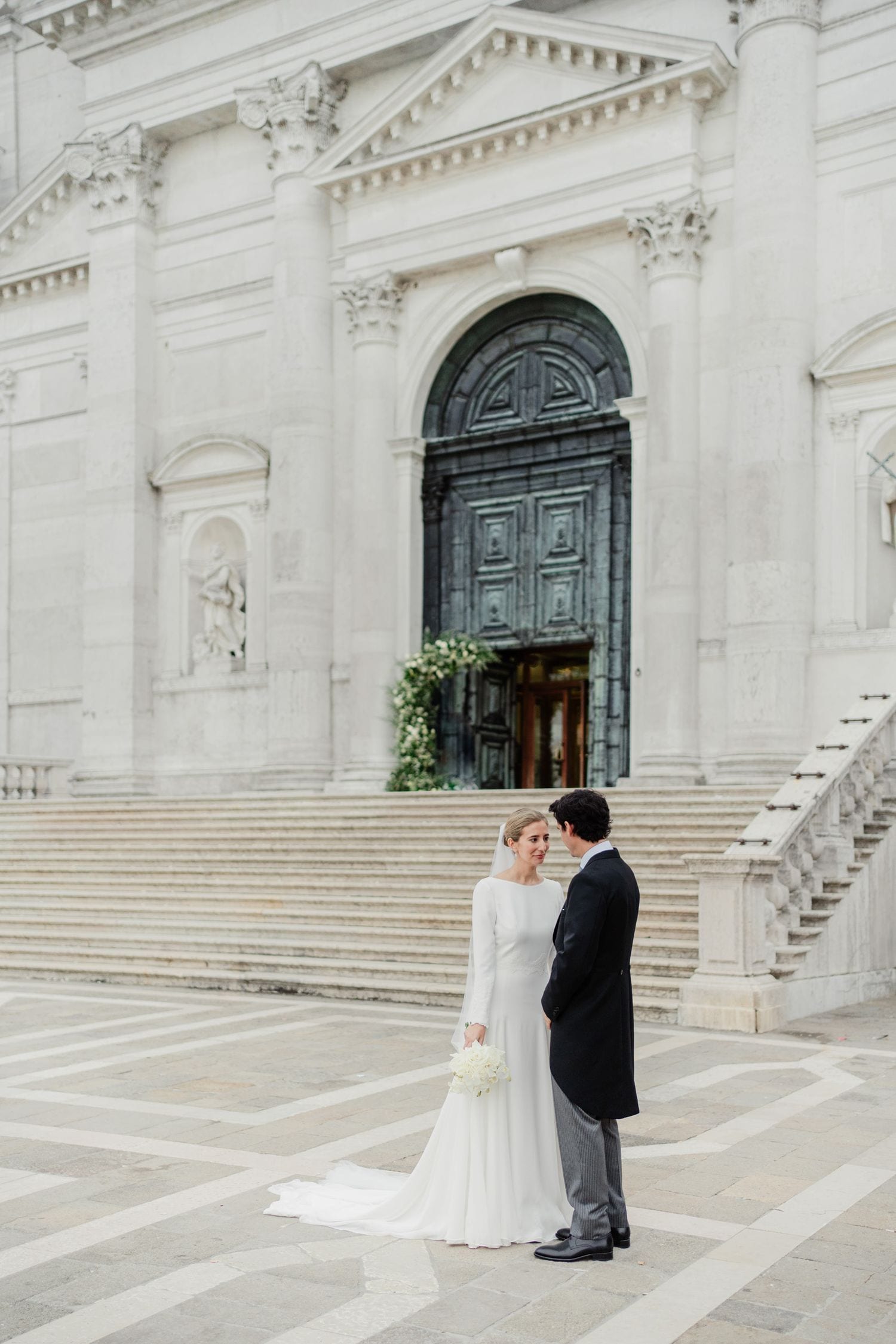 Maria e Rafael si abbracciano sui gradini de Il Redentore durante i ritratti di matrimonio a Venezia.