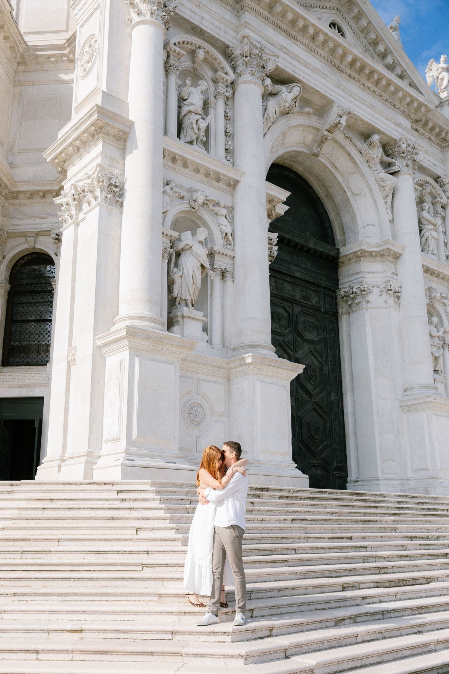 Romantic sequence on ornate white marble steps of Venetian basilica.