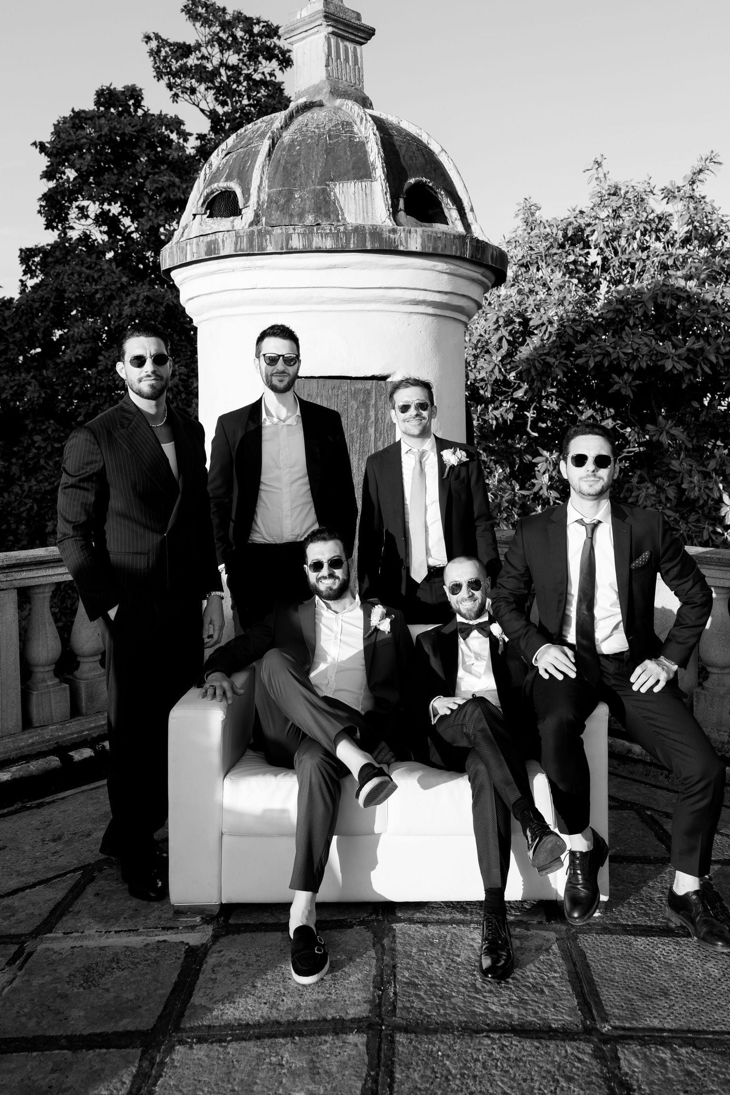Stylish group in suits poses by a domed architectural feature in black and white photography.
