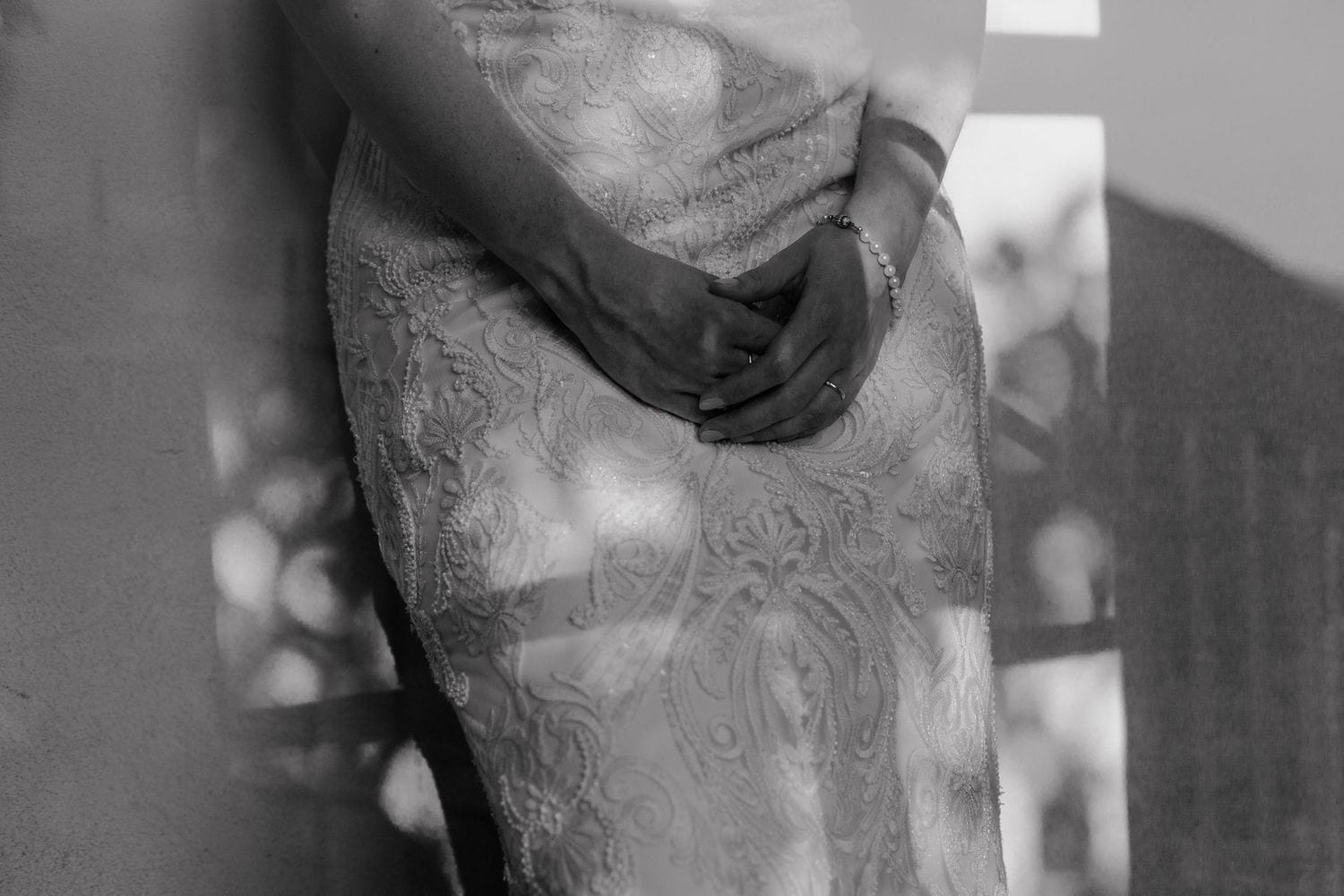 Black and white close-up photo showing an arm with elaborate tattoo details in shadow and light.