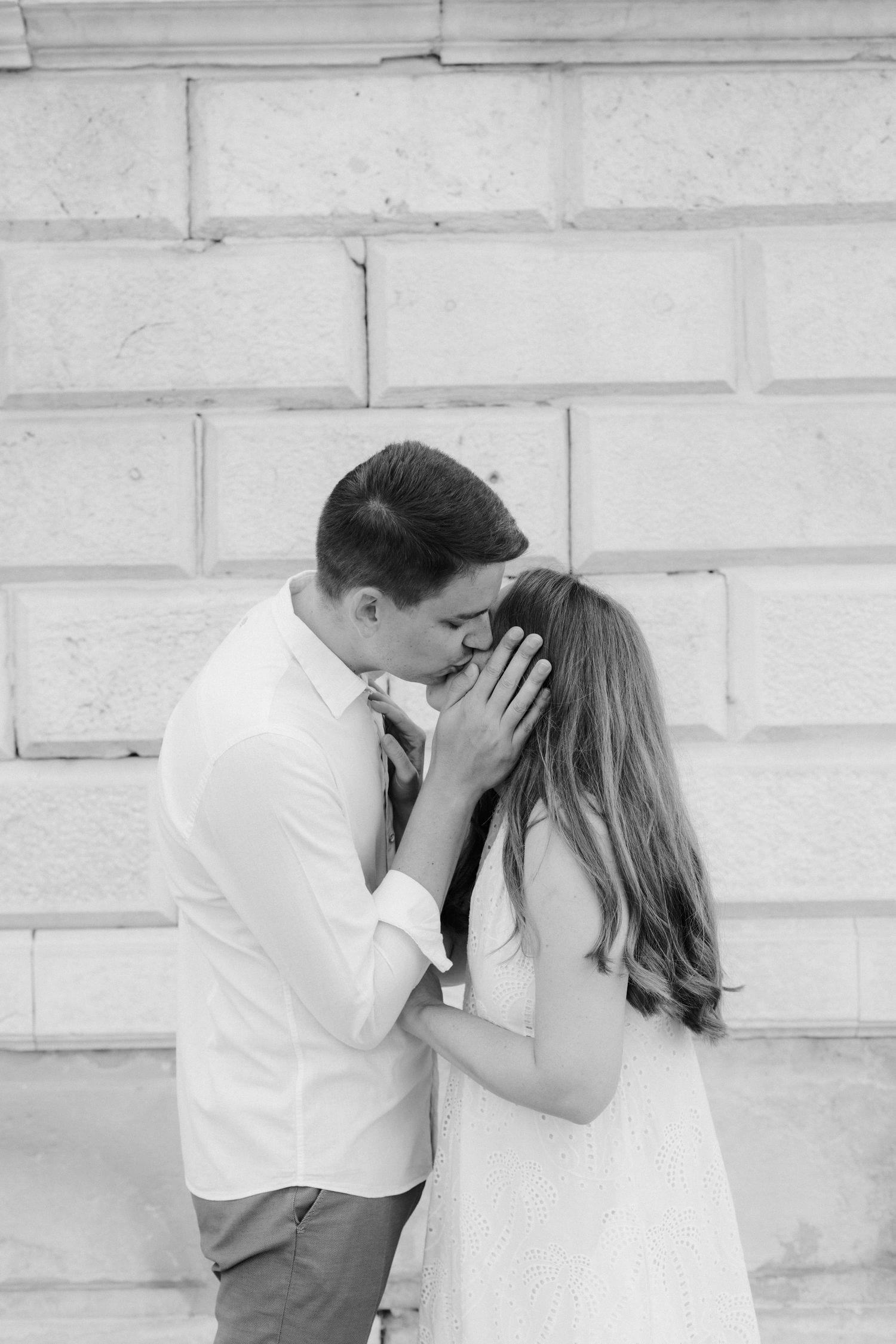 Intimate black and white portrait sequence against white stone wall.