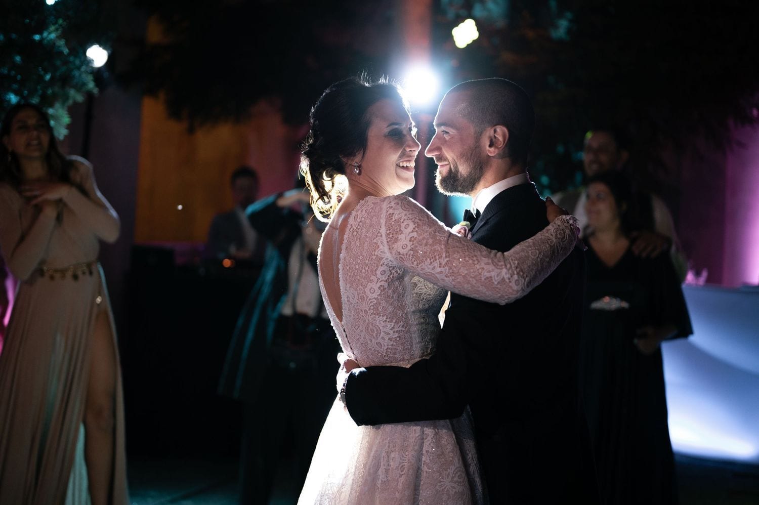 A couple shares an intimate dance under dramatic lighting at an elegant evening event.