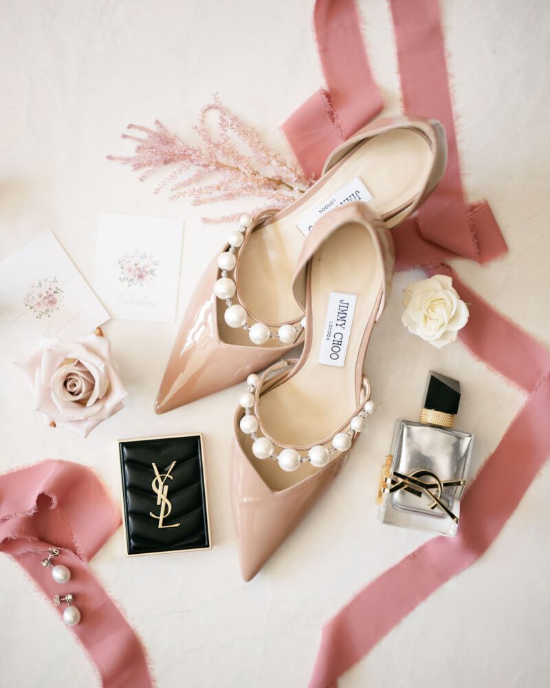 Elegant blush pink Jimmy Choo stilettos with pearl straps styled with YSL accessories and pink ribbon.