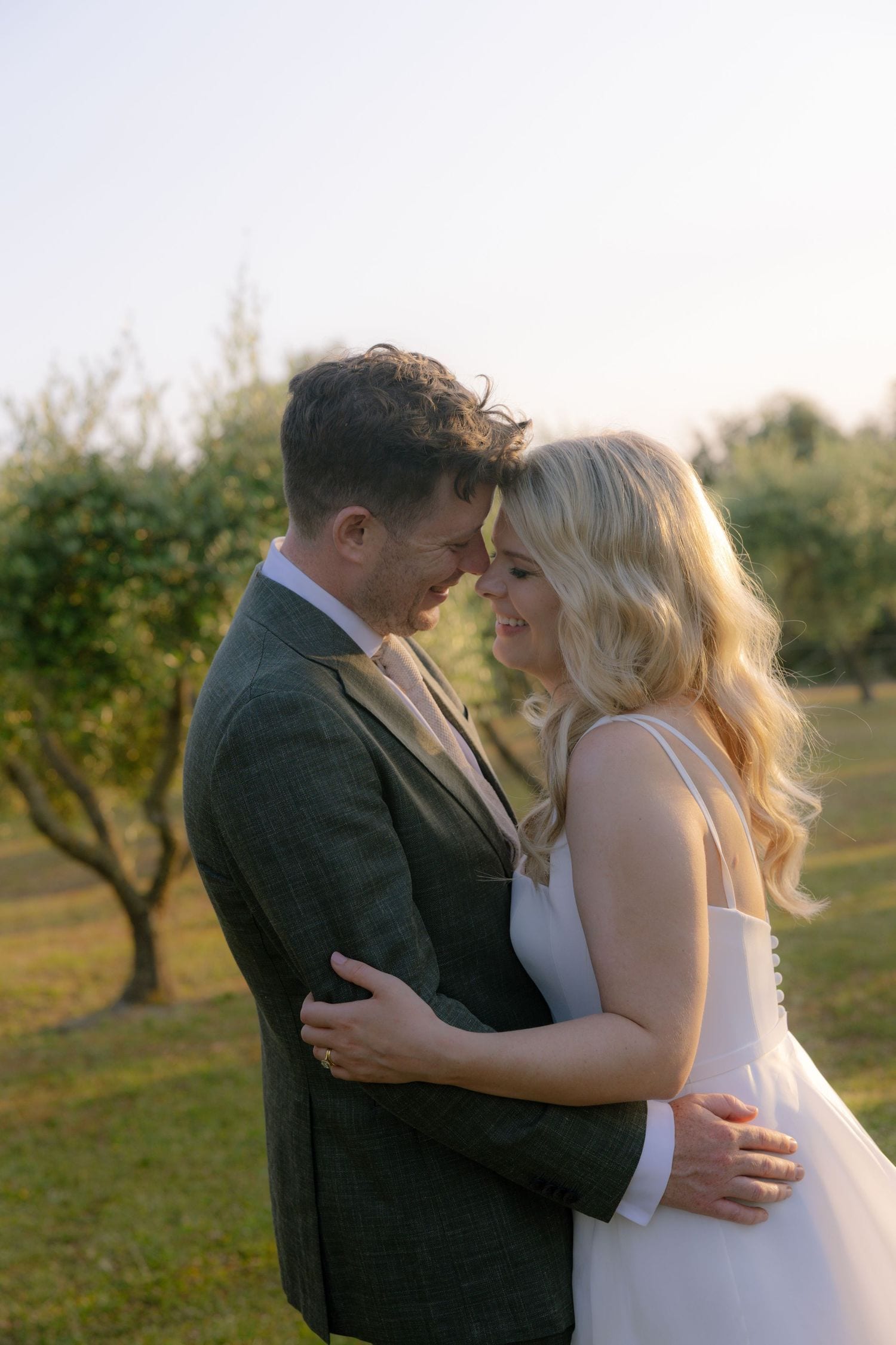 Ritratto romantico degli sposi tra gli ulivi al tramonto durante un matrimonio in Toscana.