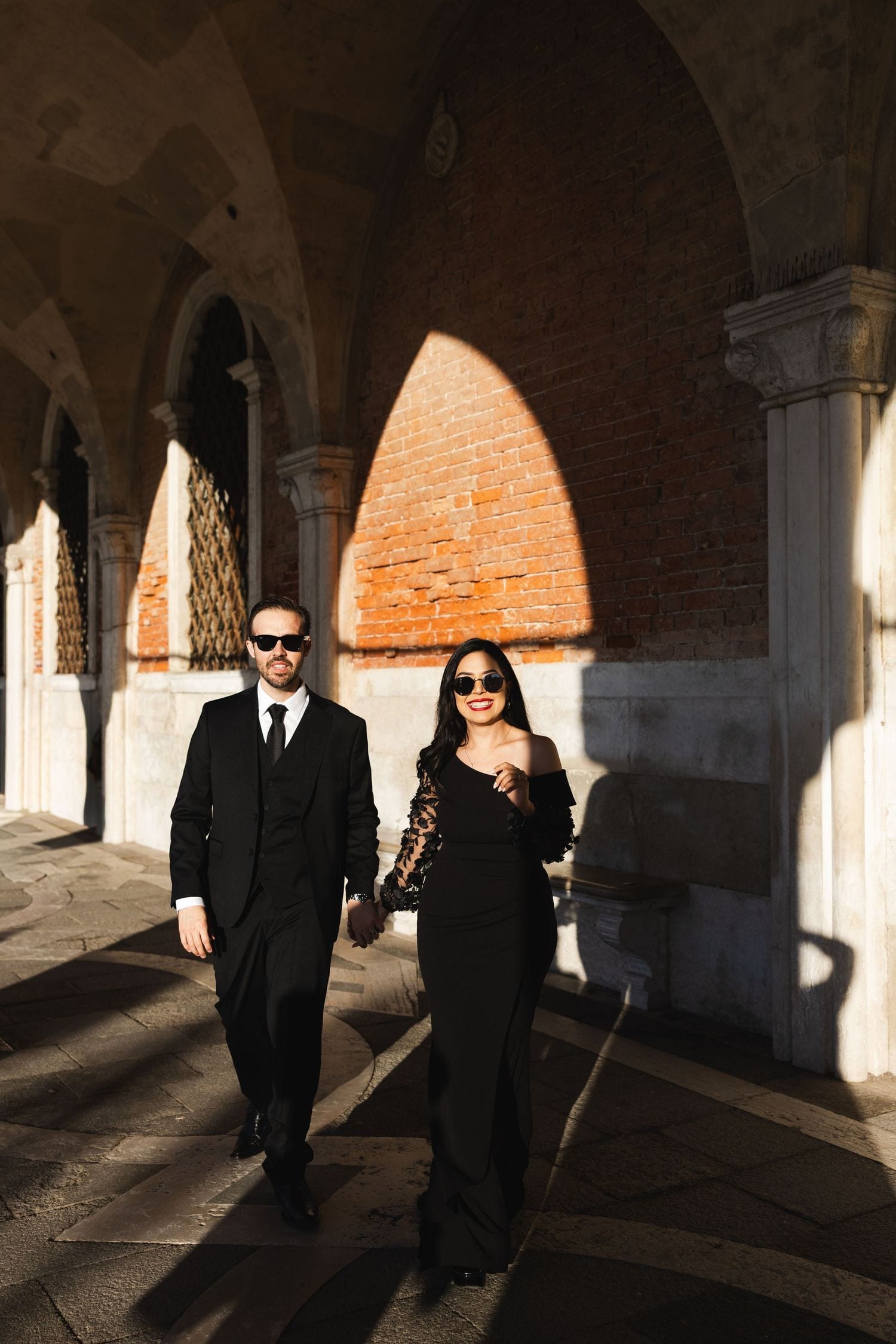 Couple walking under the arcades of San Marco with dramatic light and shadow