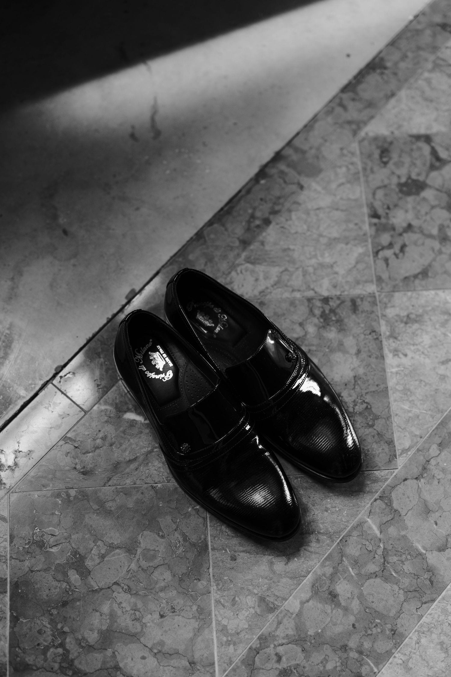 Scarpe eleganti nere fotografate sul pavimento in marmo.