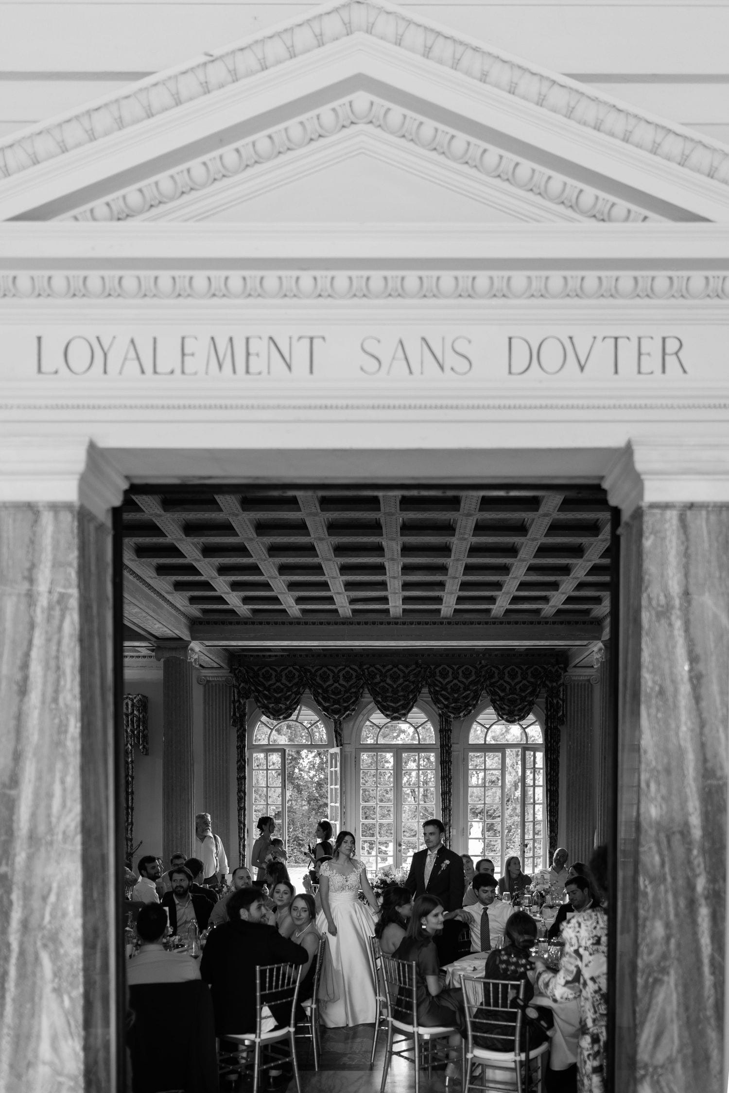 Cerimonia di matrimonio in bianco e nero sotto un ingresso architettonico classico.