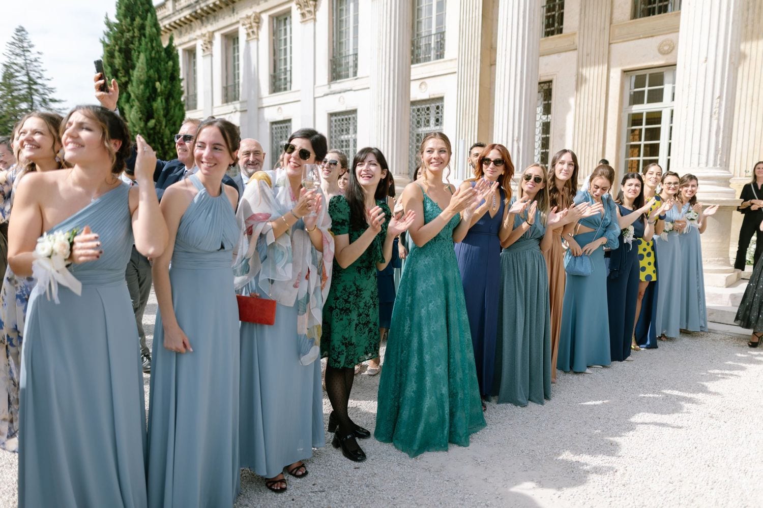 Wedding party con abiti blu e verdi davanti alla villa con colonne.