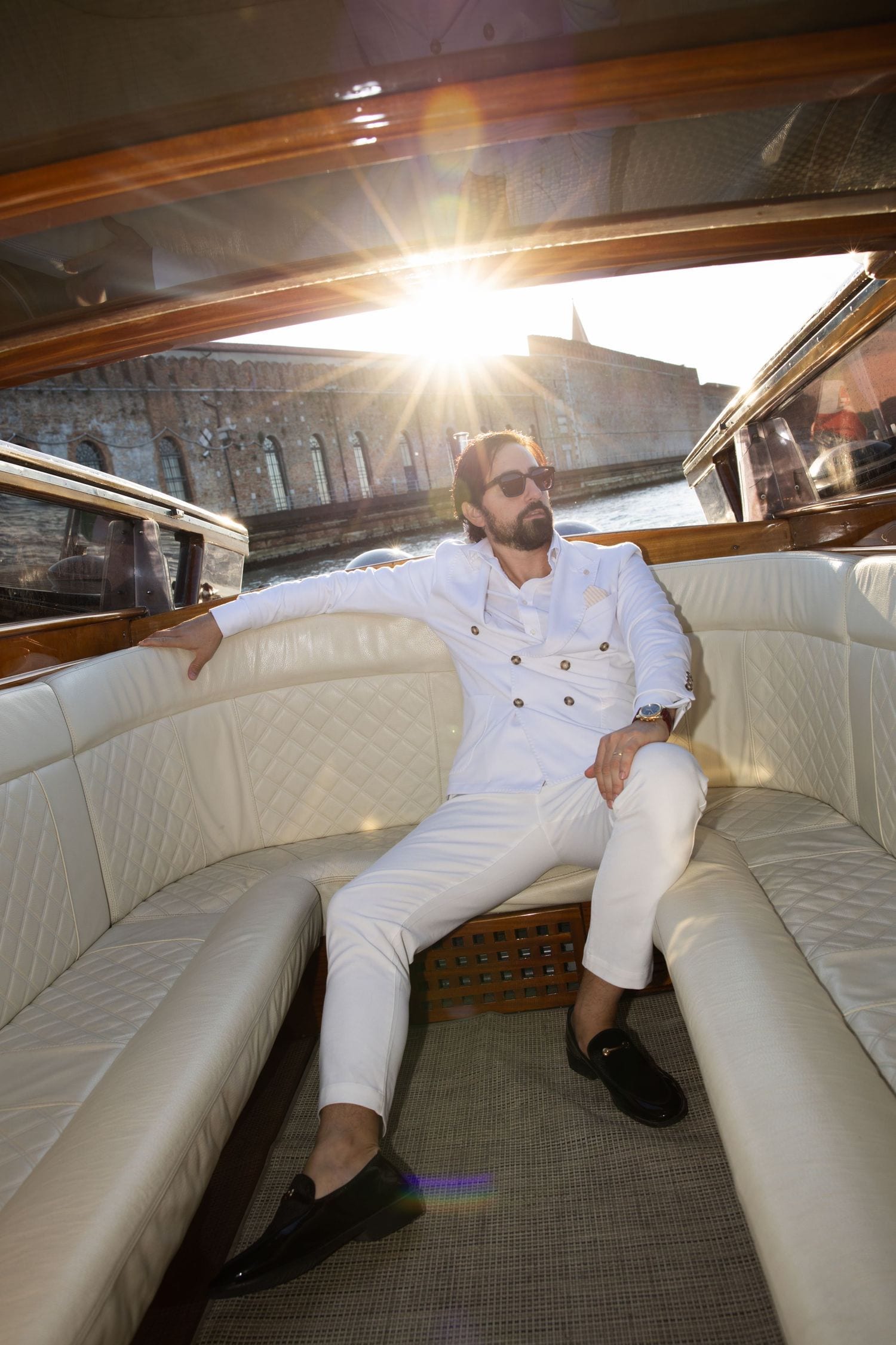 Groom in a white dress on a boat during an intimate Venice elopement