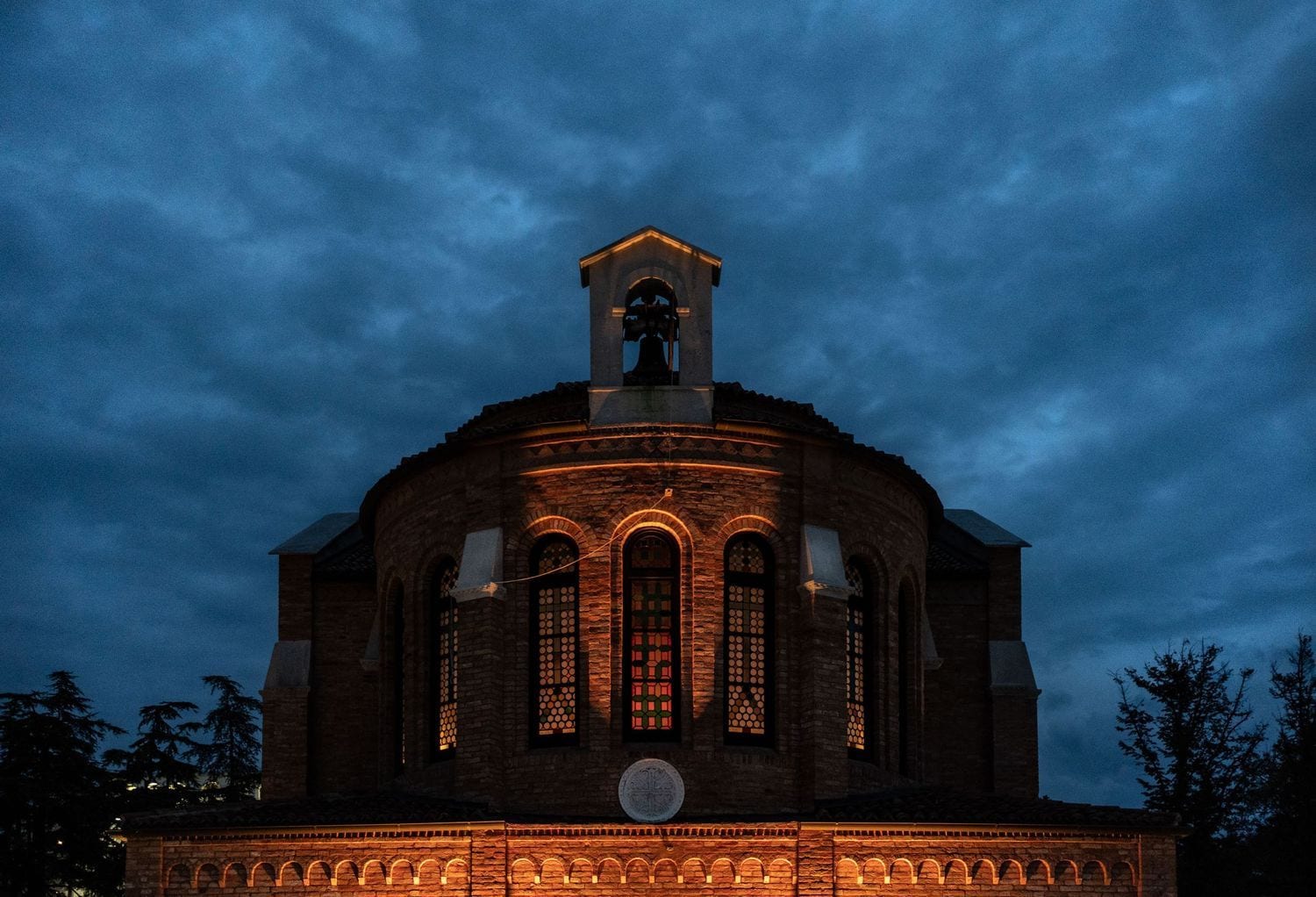 Historic brick church at the Marriot Island illuminated by warm orange lights against a dramatic dark blue cloudy evening sky.