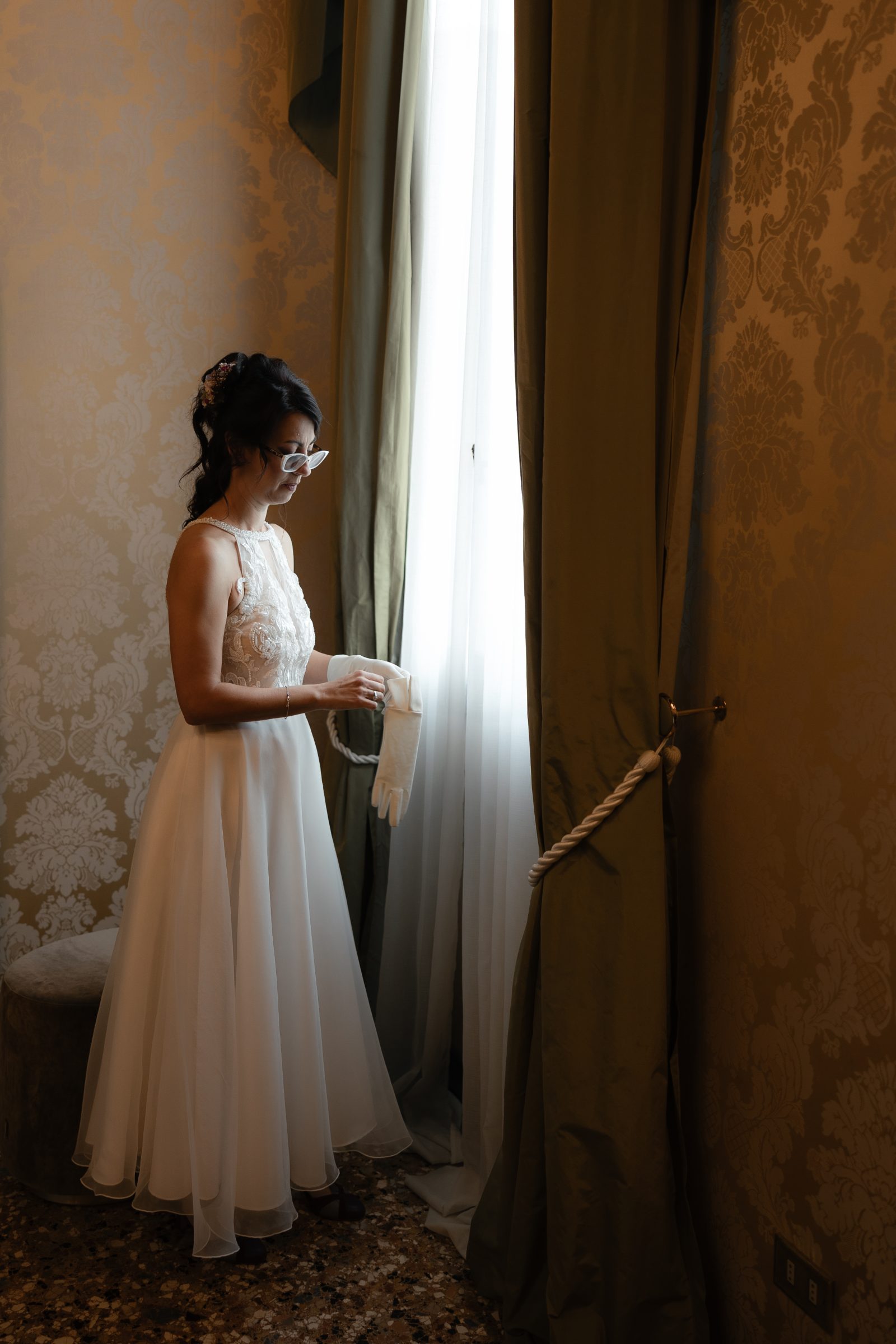 Bride getting ready beside a window before her civil wedding in Venice