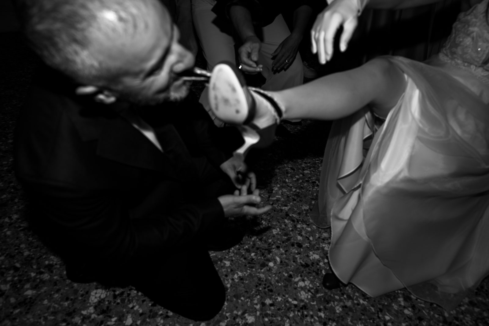 Playful black-and-white moment with the bride’s shoe during the wedding party