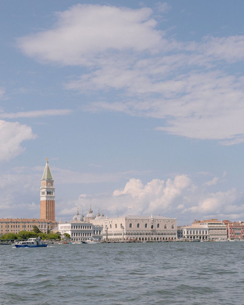 Church and bell tower seen across the lagoon under a blue sky