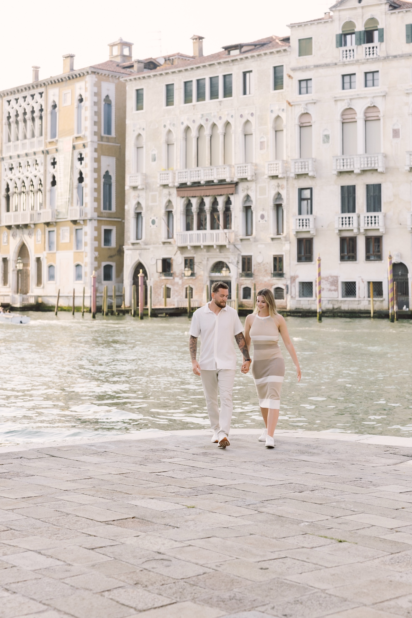Joseph and Gianna walking together beside the Grand Canal after their surprise proposal in Venice