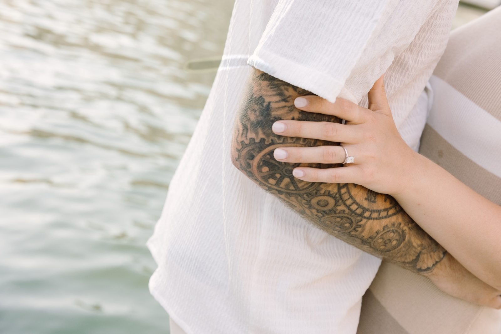 Gianna’s engagement ring resting on Joseph’s tattooed arm with Venetian water behind them