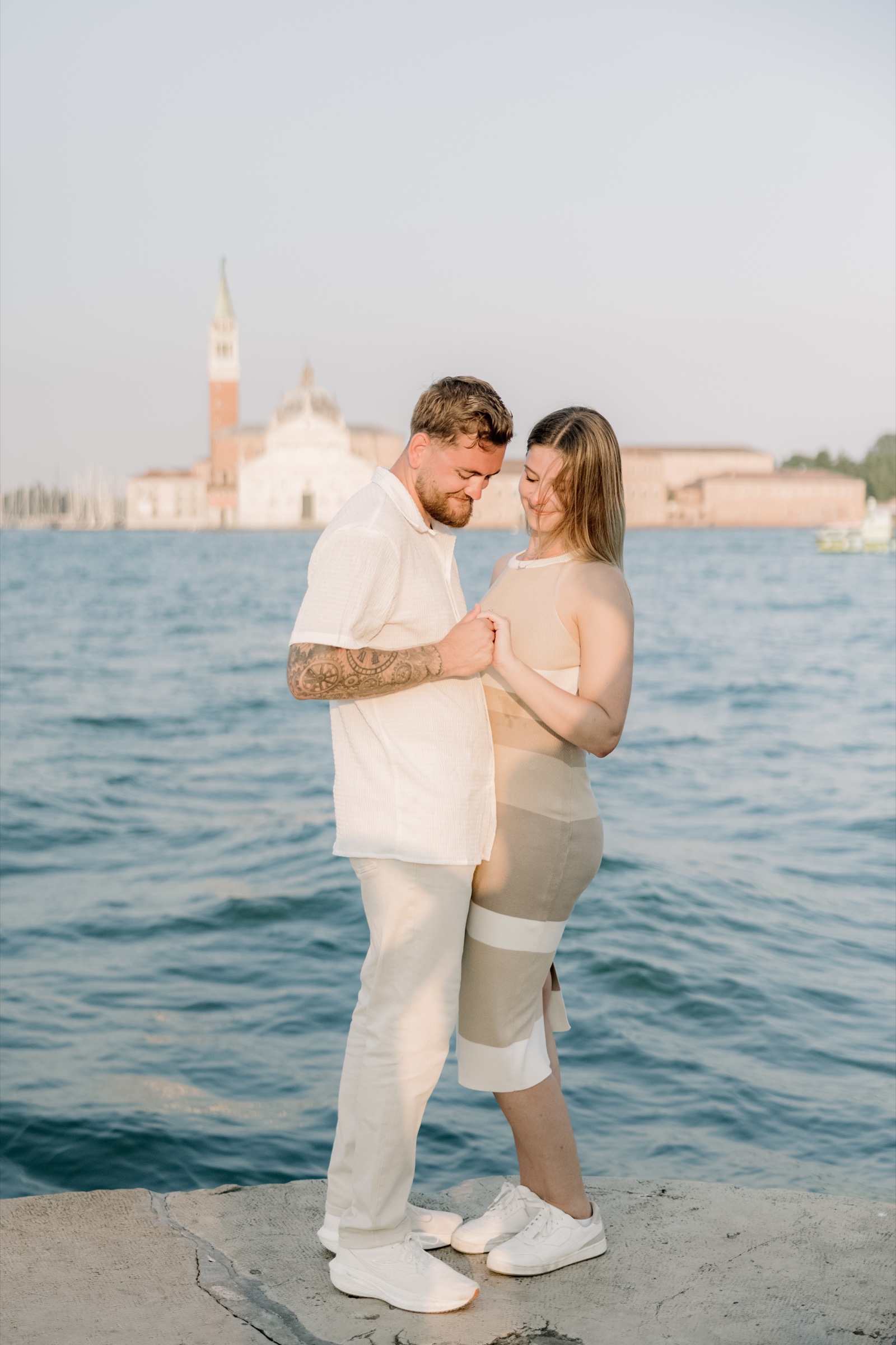 Joseph and Gianna holding hands by the Venetian lagoon with San Giorgio Maggiore behind them
