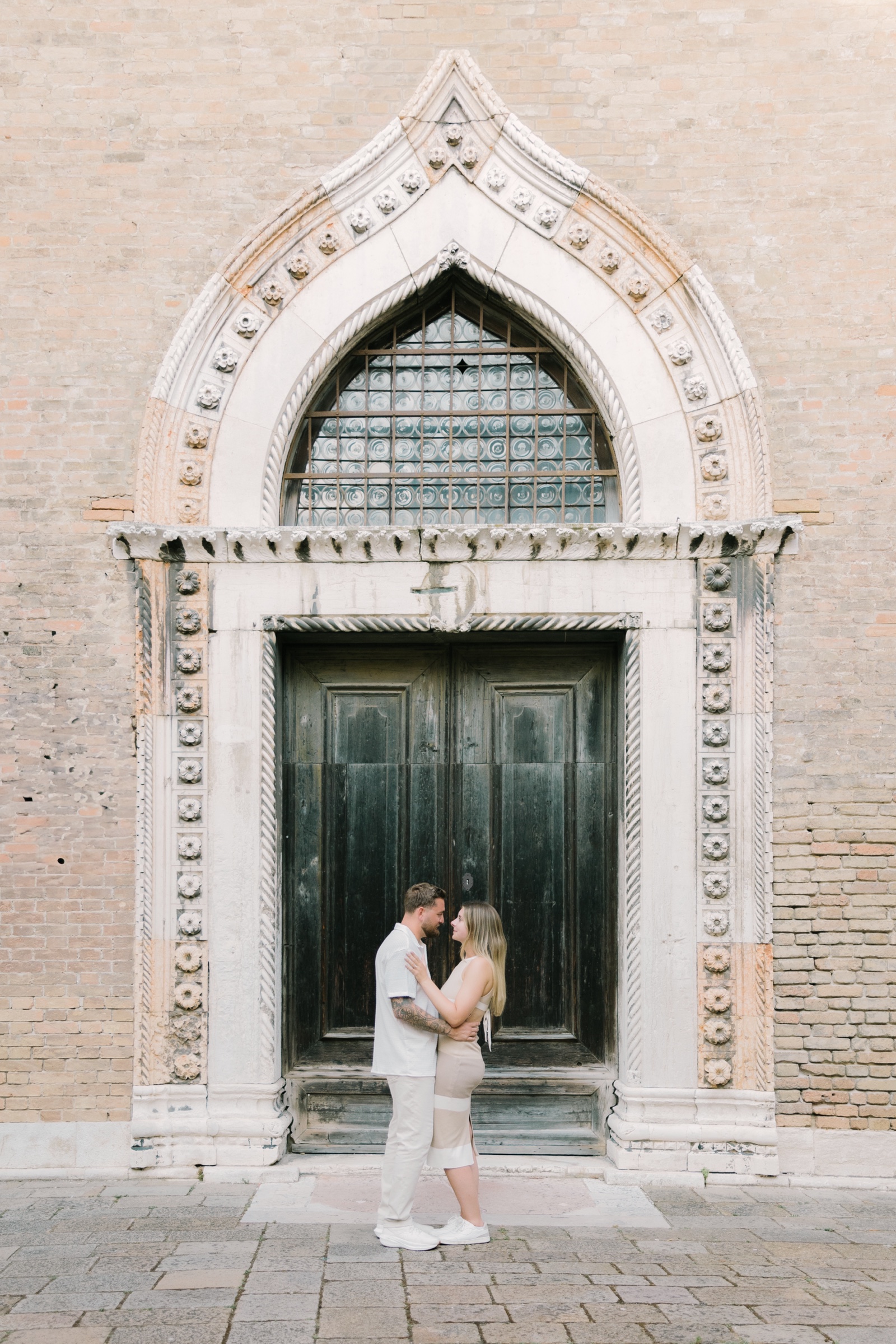 Joseph and Gianna standing beneath an ornate Gothic doorway during their engagement session in Venice